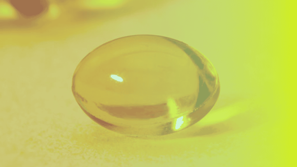 A close-up of a single yellow translucent gel capsule on a light surface with a yellow tint, symbolizing corporates wellness and modern approaches to employee health.