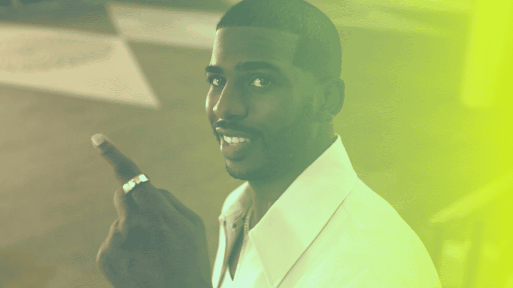 A man in a white shirt smiles and points upward with his right index finger; the image, tinted green and yellow, reflects a positive corporates wellness vibe.