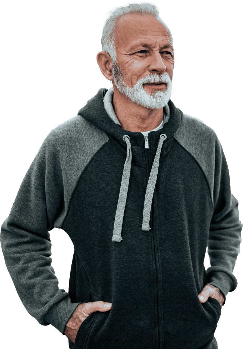 Older man with white hair and beard wearing a dark Coya zip-up hoodie, hands in pockets, looking off to the side.
