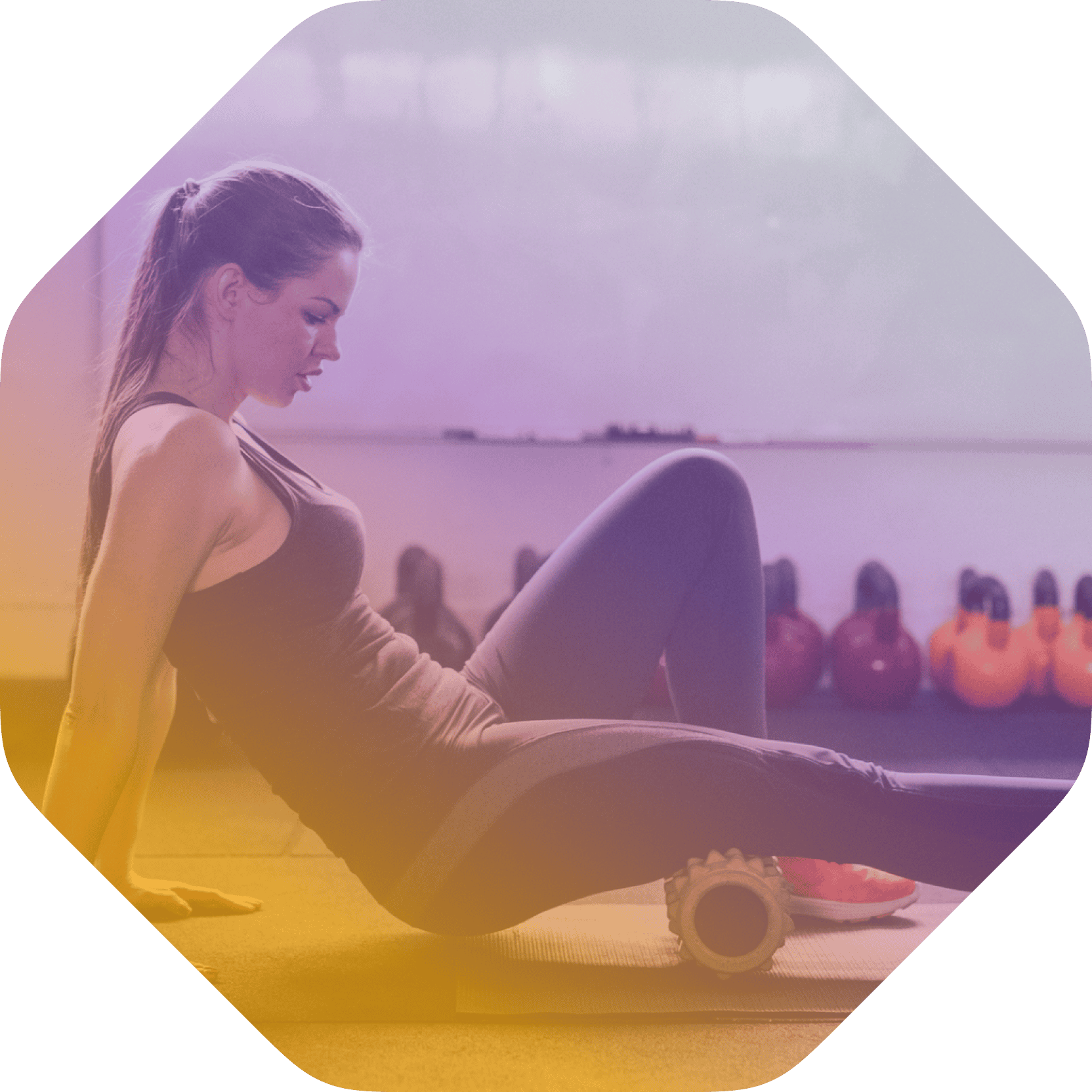 A woman in athletic wear uses a foam roller on her leg in a gym with kettlebells in the background, showcasing how coya for fitness clubs supports effective post-workout recovery.