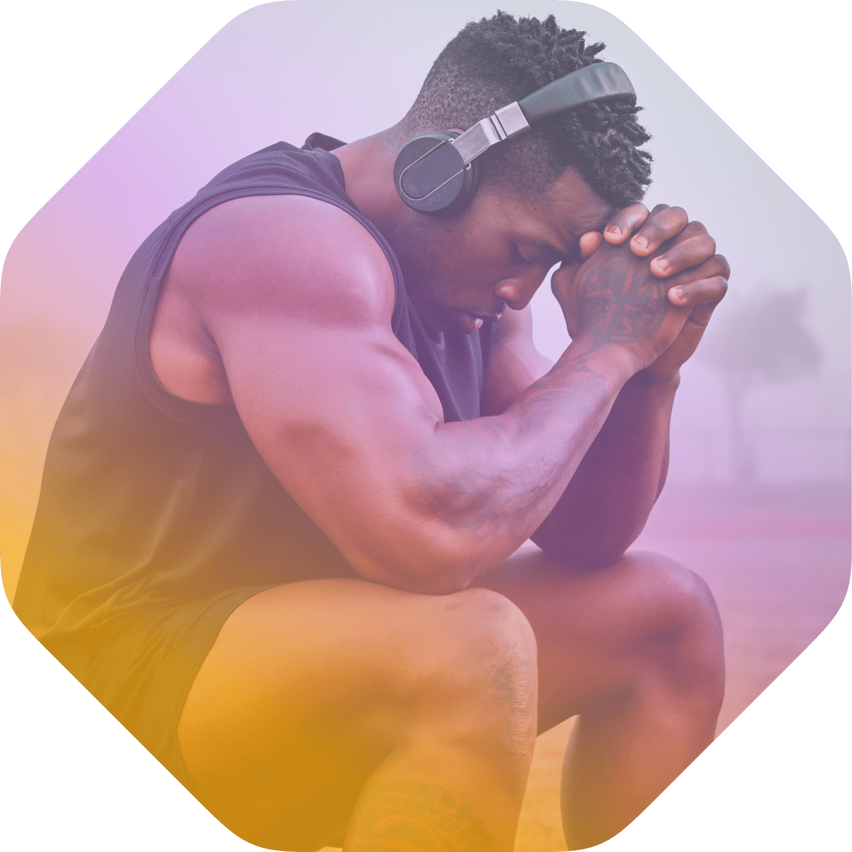 A man wearing headphones sits on one knee outdoors with his hands clasped and head resting on them, appearing focused—perfectly embodying the concentration encouraged by Coya for student athletes.