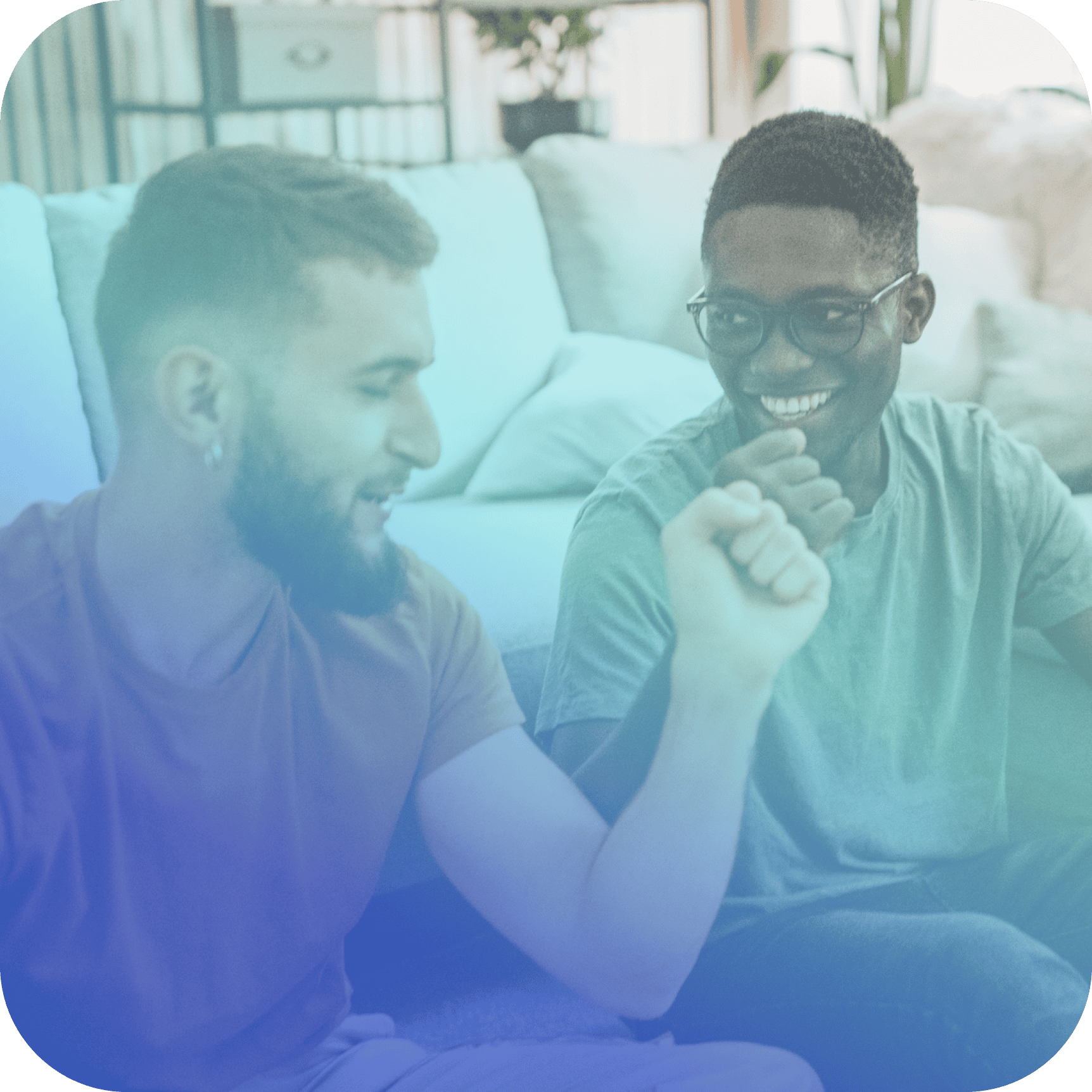 Two people sitting on the floor in a living room, smiling and appearing to celebrate or high-five—showcasing the team spirit Coya for companies inspires.