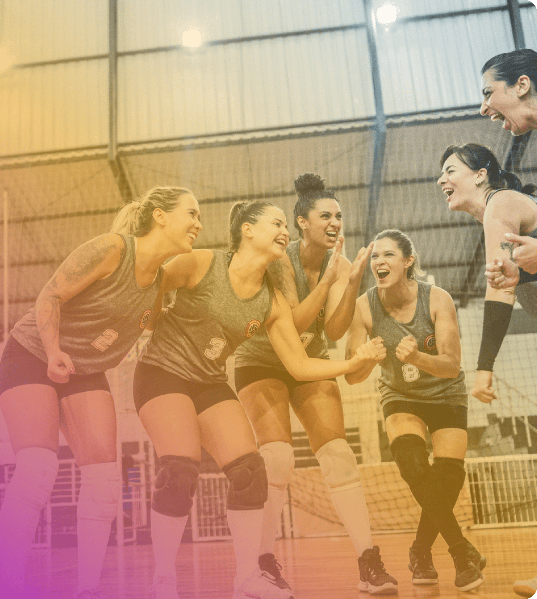 Six women in sports uniforms celebrate together on an indoor volleyball court, smiling and cheering as they gather in a group—showing the spirit that coya for student athletes inspires.