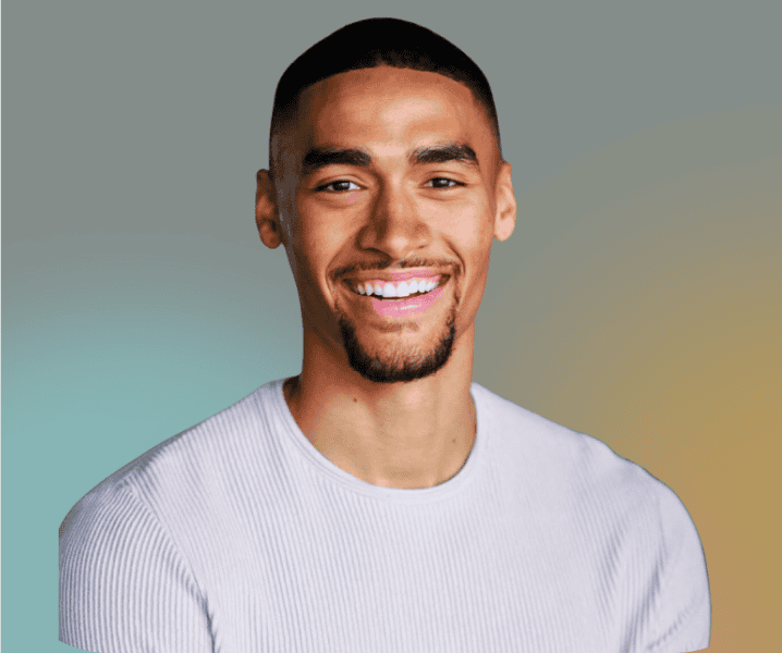 Dayna McCutchin smiles at the camera, sporting short hair and a goatee, in a light grey ribbed shirt against a gradient background.