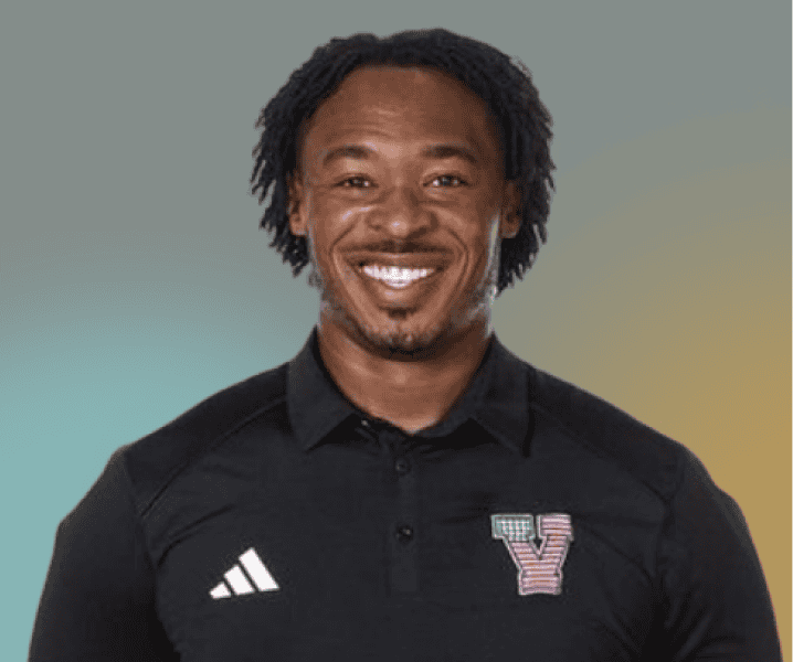 A man smiling, wearing a black collared shirt with Adidas stripes and a multicolored V patch on the left side, stands against a gradient background, reminiscent of Dayna McCutchins signature style.